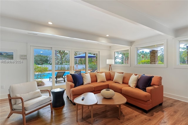 living room featuring beam ceiling, hardwood / wood-style flooring, and a wealth of natural light