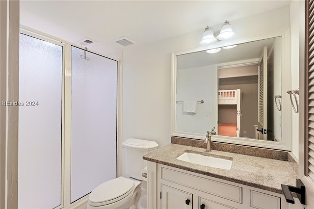 bathroom with a shower with door, vanity, and toilet