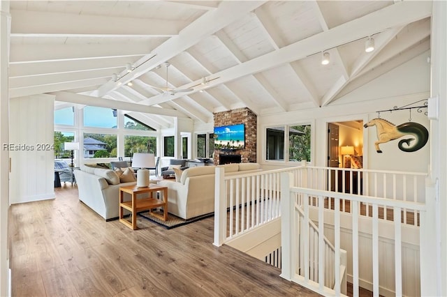 living room featuring hardwood / wood-style flooring, track lighting, a fireplace, and lofted ceiling with beams