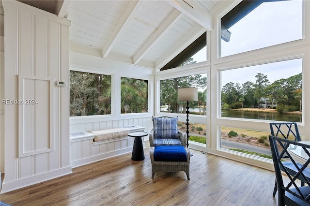 sunroom with lofted ceiling with beams and a water view