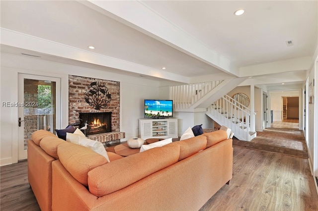 living room with a brick fireplace, hardwood / wood-style flooring, and beamed ceiling