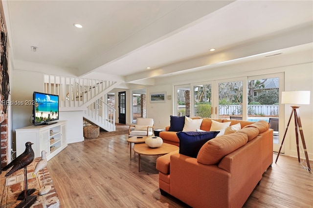 living room with french doors, beam ceiling, and light hardwood / wood-style flooring