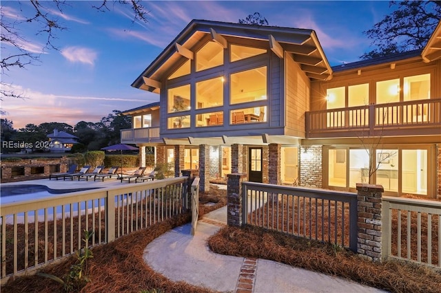 back house at dusk featuring a balcony