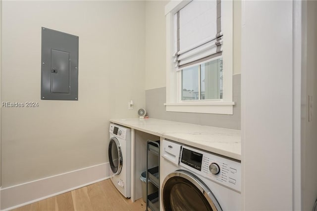 clothes washing area with washer / dryer, electric panel, and light hardwood / wood-style floors