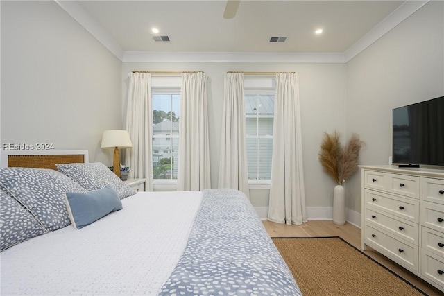 bedroom with light hardwood / wood-style flooring, ornamental molding, and ceiling fan