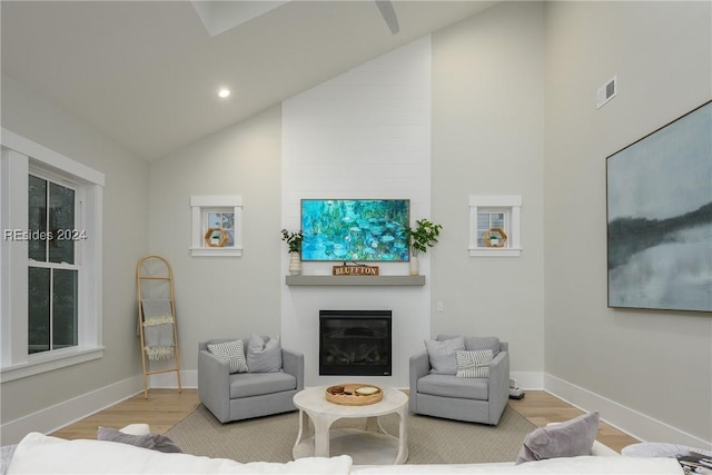 living room featuring light hardwood / wood-style flooring, a fireplace, and vaulted ceiling