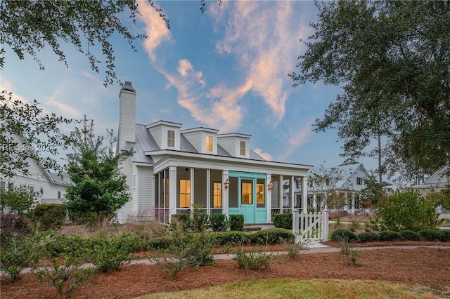 back house at dusk featuring a porch