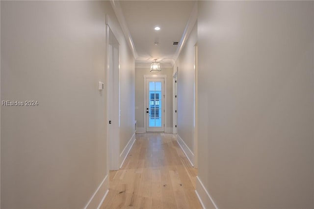 hallway with crown molding and light wood-type flooring