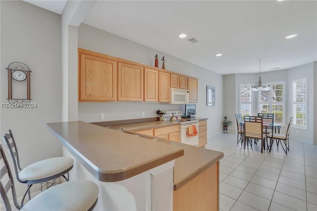 kitchen featuring white appliances, decorative light fixtures, kitchen peninsula, and light brown cabinetry