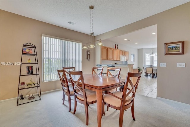 dining space with light carpet and a textured ceiling