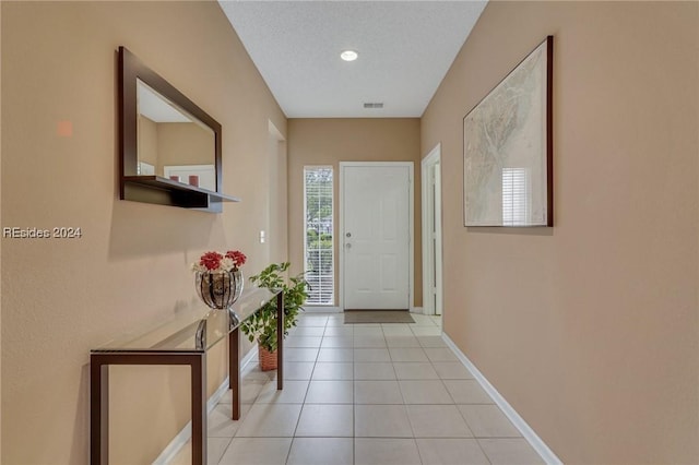 entryway with a textured ceiling and light tile patterned floors