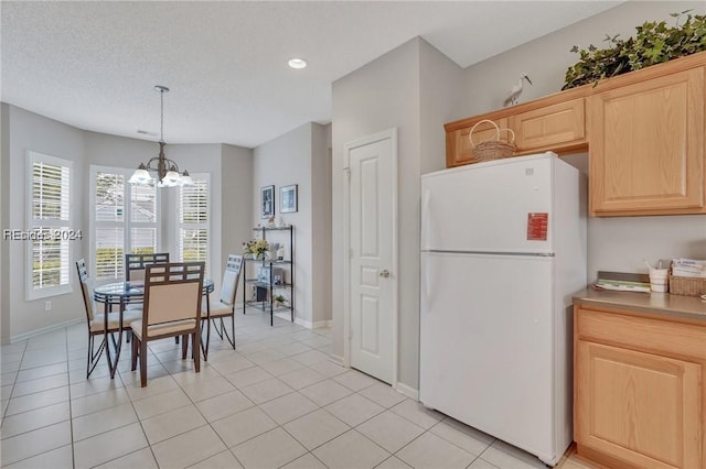 kitchen featuring decorative light fixtures, a chandelier, white refrigerator, light tile patterned floors, and light brown cabinets