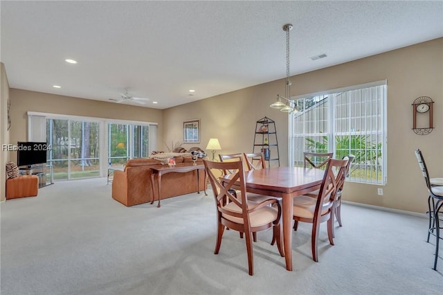 carpeted dining room with ceiling fan, a healthy amount of sunlight, and a textured ceiling