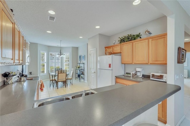 kitchen with sink, hanging light fixtures, kitchen peninsula, light brown cabinets, and white appliances