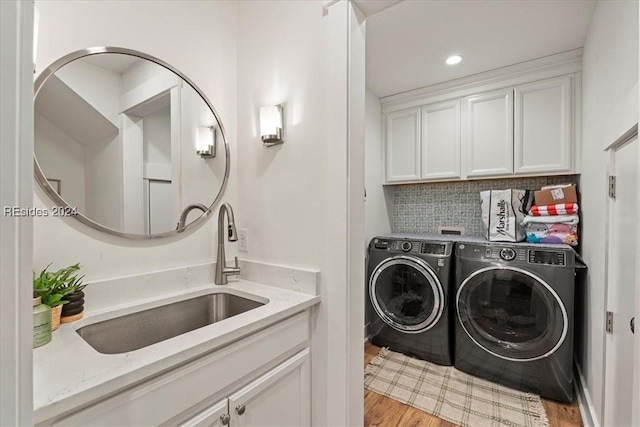 laundry room featuring cabinets, sink, washing machine and clothes dryer, and light wood-type flooring