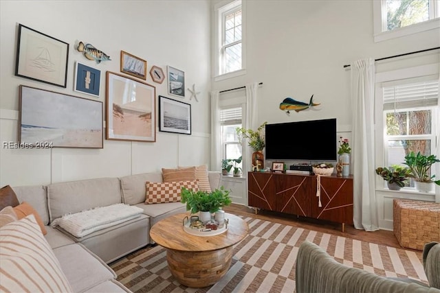 living room with plenty of natural light, light hardwood / wood-style flooring, and a high ceiling