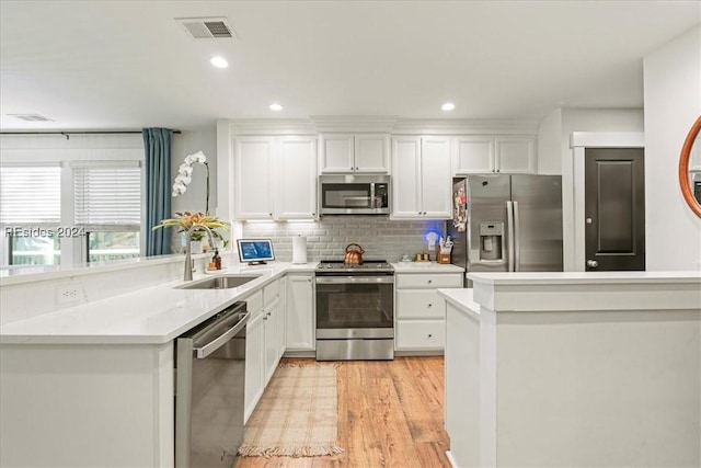 kitchen with sink, light hardwood / wood-style flooring, white cabinetry, backsplash, and stainless steel appliances