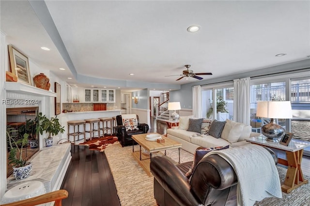 living room featuring ceiling fan, a fireplace, and light hardwood / wood-style flooring