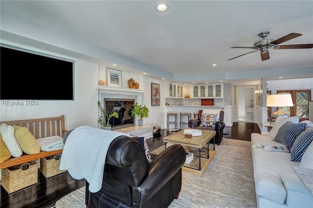 living room with hardwood / wood-style flooring, ceiling fan, and a fireplace