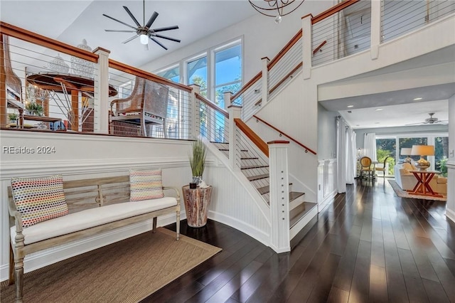 stairway with a high ceiling, hardwood / wood-style floors, and ceiling fan