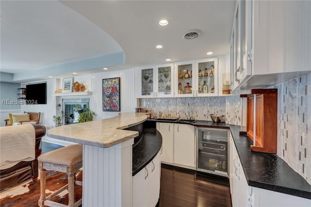 kitchen featuring dark wood-type flooring, a breakfast bar, tasteful backsplash, a center island, and white cabinets