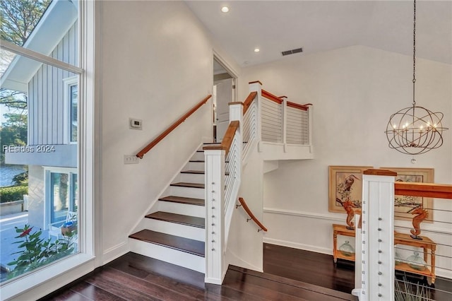 staircase with hardwood / wood-style flooring, a wealth of natural light, and a chandelier