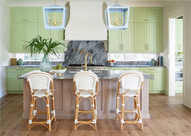 kitchen featuring premium range hood, a breakfast bar area, dark stone countertops, and green cabinetry