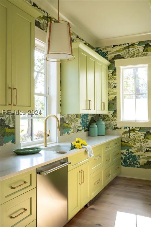 kitchen with stainless steel dishwasher, a healthy amount of sunlight, light hardwood / wood-style floors, and cream cabinetry