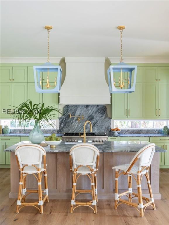 kitchen with premium range hood, pendant lighting, a breakfast bar area, dark stone counters, and decorative backsplash