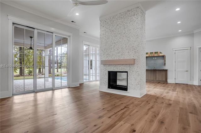 unfurnished living room with ceiling fan, a multi sided fireplace, ornamental molding, and hardwood / wood-style floors