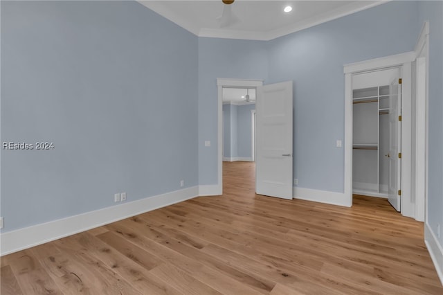 unfurnished bedroom with ornamental molding, light hardwood / wood-style flooring, ceiling fan, and a closet