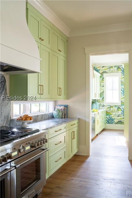 kitchen featuring custom exhaust hood, plenty of natural light, green cabinets, and high end stainless steel range