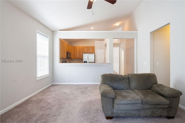 living room featuring a wealth of natural light, vaulted ceiling, light colored carpet, and ceiling fan