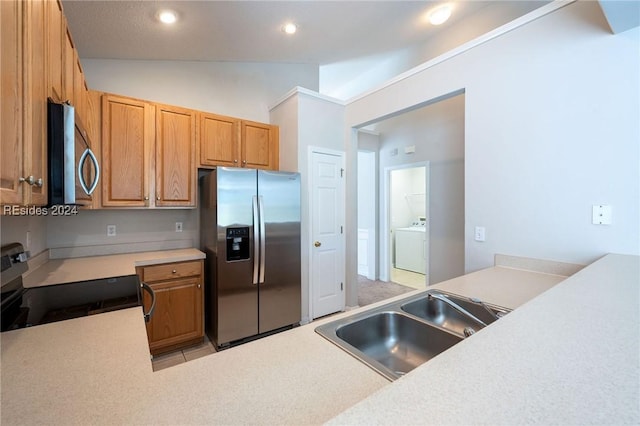 kitchen featuring lofted ceiling, sink, stainless steel appliances, light tile patterned flooring, and washer / dryer