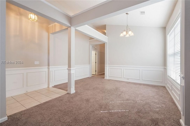 empty room featuring a notable chandelier and light colored carpet