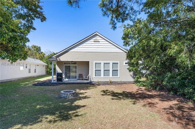 rear view of property featuring a fire pit, a lawn, and a patio area