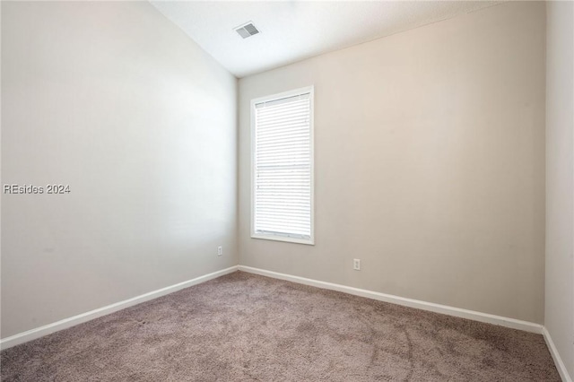 empty room featuring lofted ceiling and carpet flooring