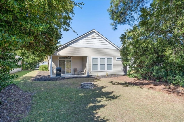 back of house with an outdoor fire pit and a yard