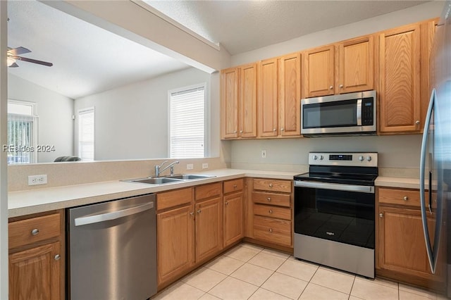 kitchen featuring sink, ceiling fan, stainless steel appliances, light tile patterned flooring, and vaulted ceiling