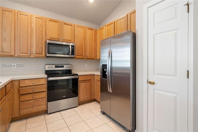 kitchen with light tile patterned flooring, stainless steel appliances, and vaulted ceiling