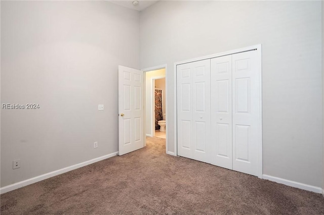 unfurnished bedroom featuring a high ceiling, carpet flooring, and a closet