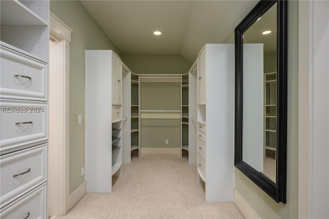 walk in closet with vaulted ceiling and light carpet