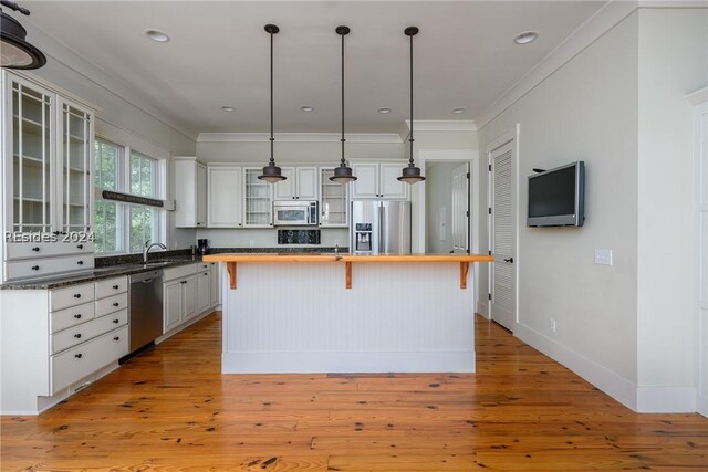 kitchen with a breakfast bar area, white cabinetry, hanging light fixtures, appliances with stainless steel finishes, and a kitchen island