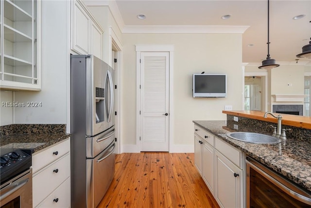 kitchen with wine cooler, sink, appliances with stainless steel finishes, pendant lighting, and white cabinets