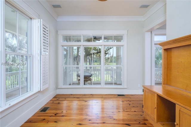 unfurnished dining area featuring crown molding, light hardwood / wood-style flooring, and plenty of natural light