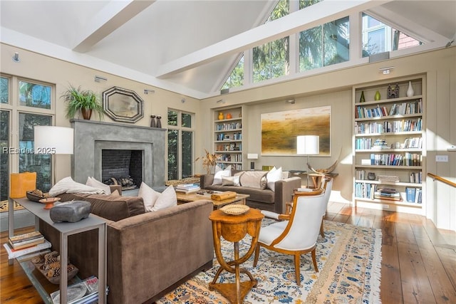 living room with built in shelves, wood-type flooring, a premium fireplace, and high vaulted ceiling