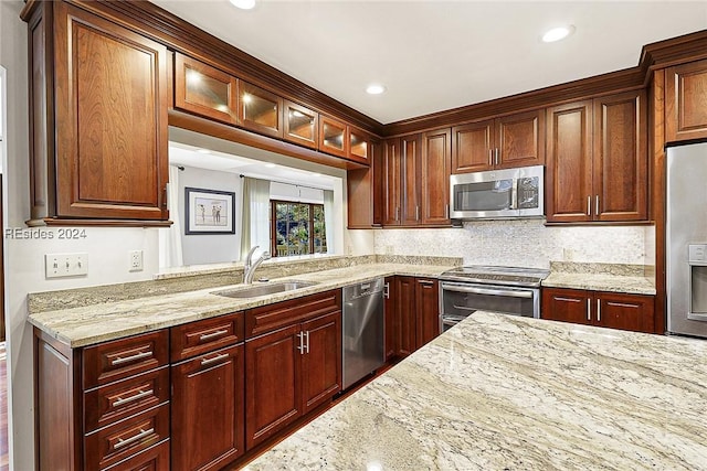 kitchen with light stone counters, appliances with stainless steel finishes, sink, and tasteful backsplash