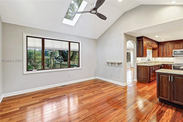 kitchen featuring light stone counters, ceiling fan, appliances with stainless steel finishes, and dark hardwood / wood-style flooring