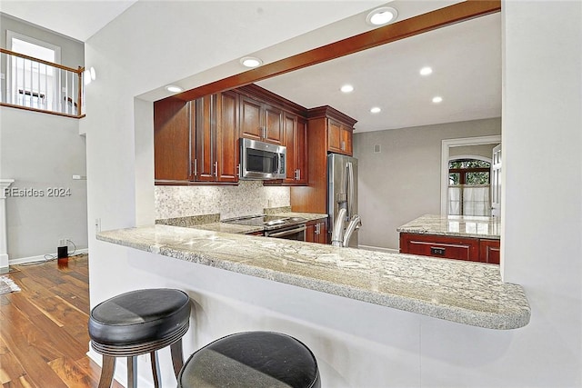 kitchen with stainless steel appliances, light stone countertops, and kitchen peninsula