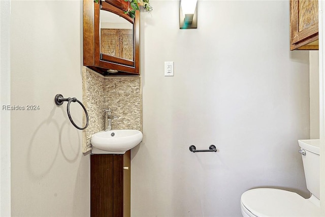 bathroom with toilet, vanity, and decorative backsplash